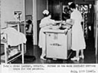 Nurses at hospital in Sioux Lookout are serving trays for patients in the main corridor July 1959