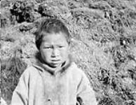 [Portrait of an unidentified Inuit child wearing a parka in front of a mound of dirt and grass, possibly Nunavut]. Original title : Half breed Eskimo children (American), [Nunavut?] n.d.