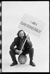 Squashing Rumours that the World is Round : Leo Ferrari sitting on a Globe holding a placard n.d.