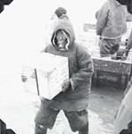Unidentified Inuit man unloading cargo from the M.V. Regina Polaris 1952