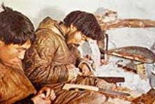 Two unidentified Inuit men sharpening their knives 1952?