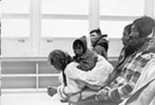 Group of Inuit seated inside an unidentified building [graphic material] : possibly they are attending a church service 1965