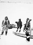 Three Inuit with their sleds, N.W.T. [Nunavut] [graphic material] : [ca. 1964] [ca. 1964].