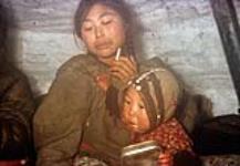 Young Inuit woman and an infant sitting inside a tent [graphic material] n.d.
