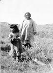 Inuk woman and child walking in grass at Kugluktuk (formerly Coppermine), Nunavut n.d.