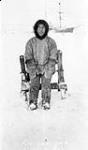 Inuk man "Kalooguk standing in front of a wooden frame in snow with a ship in the background 1909