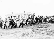 Large group of Inuit children in a foot race on grass n.d.