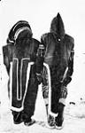 Close-up view of an Inuit couple (from the rear) wearing traditional parkas from the Kugluktuk region 1930