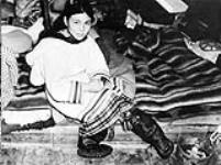 [Inuit girl Pitula sitting on blankets indoors. Picture taken at Lake Harbour, N.W.T. Summer 1939]. Original title: "Pitula" a supposedly beautiful Eskimo girl, taken at Lake Harbour, N.W.T. Summer 1939 Summer 1939