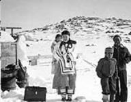 Inuit men and women [Ikirat Paipaaq in back, Pia Paniaq, Nauyarlak Tassugat smoking cigarette, and Paul Tassugat in Piniraq] , Baffin Island (Qikiqtaaluk), Nunavut n.d.