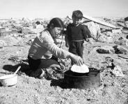 A Chesterfield Inlet (Igluligaarjuk) Inuk mother cooks bannock in a frying pan over a kerosene lamp fire n.d.