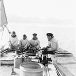 Four Inuit men sitting on a Peterhead boat sailing along George River, Quebec 1948.