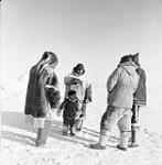 Inuit and white men standing around an Inuk boy 1949