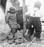 Inuit children and a woman sitting outside a tent 1949
