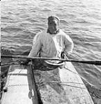 An Inuk in a kayak at Puvirnituq holds on to the pontoon of the seaplane "Norseman" 1949