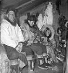 [Jorgen Klengenberg seated beside Charlie Avakana, who is playing a fiddle. Elva Avakana (later Pigalak), the sister of Charlie, is kneeling beside him. Rymer Point, Nunavut.] 1950.