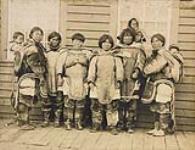 Inuit women and children in front of a frame building at Kuujjuarapik, (formerly Great Whale River), Quebec [graphic material] ca. 1901-1904.