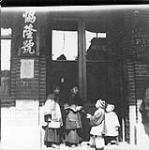 [Four children standing in storefront doorway] 1897.