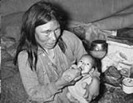 Inuit woman (Daisy) feeding her baby while seated in a tent in Chesterfield Inlet (Igluligaarjuk), Nunavut 1948.