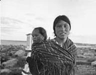 Inuit woman [Alice Sakitnaaq Tugak] carrying her baby [Rose Ooloooyukn] in Chesterfield Inlet (Igluligaarjuk), Nunavut 1948.