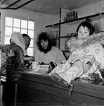 [Joe Milukshuk (an Inuk assistant) and his daughter do a little trading with a customer] Original title: Joe Milukshuk - the Eskimo assistant and the daughter do a little trading with a customer 1953