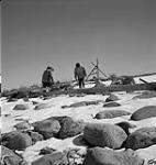 R.C.M.P. Corporal Jim Davies and a man (possibly an Inuit guide) making a stop for food during their trip from Moose Factory Island, Ontario, to Great Whale [Kuujjuarapik], Quebec January, 1946.