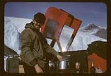 No. 24 - Man cooking beside snowmobile 1957-1958.
