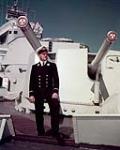 Midshipman B.A. Rogers in front of cruiser HMCS ONTARIO's main guns 1957