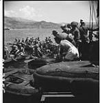 Ratings in HMCS Prince Henry lower rubber boats in the water while troops prepare to pile aboard August 24, 1944.