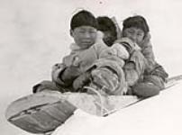 [Three Inuit children on a toboggan] [between 1928 and 1944].