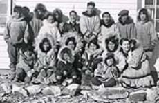 Outside Mission House at Cambridge Bay. Anna [Rokeby-Thomas] in front row (right) with Eskimo child [between 1934 and 1939].