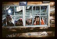 Four children looking inside through a window, Aklavik, N.W.T [ca. 1956]