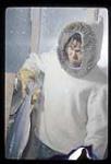 Man [possibly Johnny Morgan] glazing Arctic char, Kangiqsualujjuaq, Quebec [between July 16-26, 1960].
