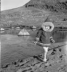 [Young child wearing a parka walking on the beach] [between 1956-1960]