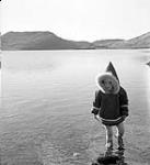 [A young child wearing a parka walking in the water] [between 1956-1960]