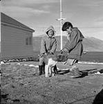 [Two children playing with a dog, Pangnirtung, Nunavut] 1960