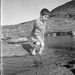 [Young boy playing in a small pool of water] [between 1956-1960]