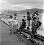 [Group of children walking along a boardwalk and playing on trolley, Iqaluit, Nunavut] 1960