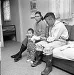 [Man [Peter Kilabuk] and woman [Mukpaloo] sitting on a couch with a child [likely Lena], Niaqunngut, Iqaluit, Nunavut] 1960