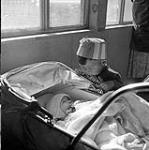 [Young boy looking at a baby in a carriage, Niaqunngut, Iqaluit, Nunavut] 1960