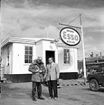 [Captain Walter Jamme (USAF) (right) and Bob (left) of Imperial Oil standing outside an Imperial Esso Dealer, Iqaluit, Nunavut] 1960