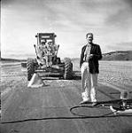 [Gordon Hollingsworth standing in front of a tractor, Iqaluit, Nunavut] 1960