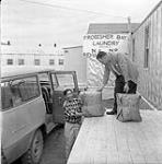 [Two men unloading packages at the laundry facility, Iqaluit, Nunavut] 1960