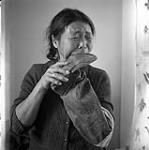 [Ikalu chewing on a new boot to soften it, Kinngait, Nunavut] 1960