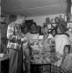 [Group of people standing behind a sealskin rug held by Bill Larmour, Killiniq, Nunavut] 1960
