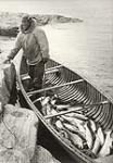 [Man standing in a canoe filled with arctic char, Ungava Bay region, Nunavut] 1960