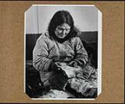 [Cotton print house dress made in Mother Hubbard style covers this Inuk woman's fur clothing, as she sits to sew] Original title: Cotton print house dress made in Mother Hubbard style covers this Eskimo woman's fur clothing, as she sits to sew 1949