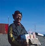 Inuit man holding box of food [Henry Augayok Shamee] 1979.