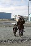 Inuit woman [Lucy Kaviok] and child [Richard Kaviok] carrying box, Arviat 1979.