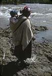 Femme des Premières Nations [Angeline (Brown) Tommy] portant un enfant [Augustine Morris] pendant la pêche [1947]